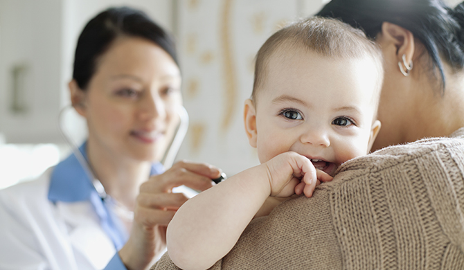 Mother holding baby while she is being examined